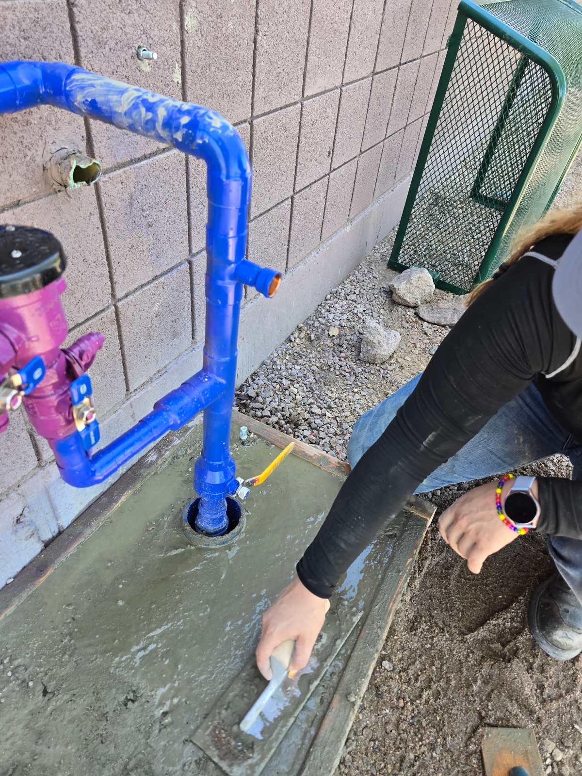 Western Sky Plumbing technician finishing the concrete pad for a commercial backflow preventer in Phoenix