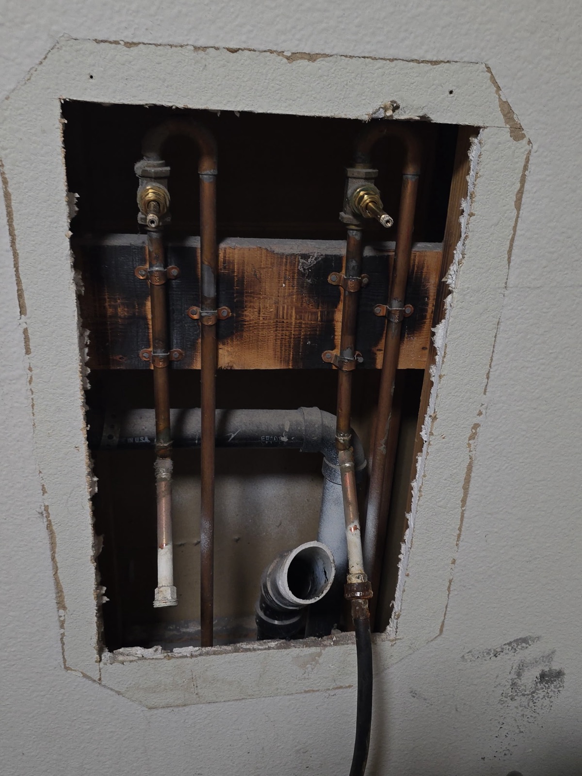 Opened drywall exposing water-damaged framing and supply lines before an in-wall leak repair in Phoenix
