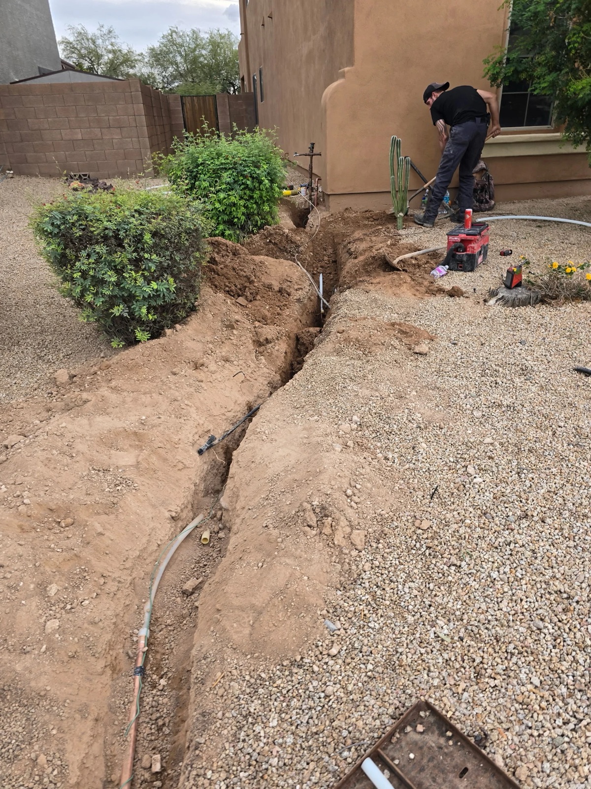 Excavated trench for a residential water line leak repair through desert landscaping in Phoenix
